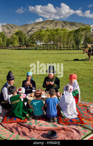 Kasachisch-Familie in traditioneller Kleidung beten vor dem Picknick Essen in Weiden bei bleibt Kasachstan Stockfoto