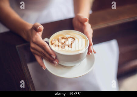 Hände der Braut mit Latte Art Kaffee Tasse Stockfoto