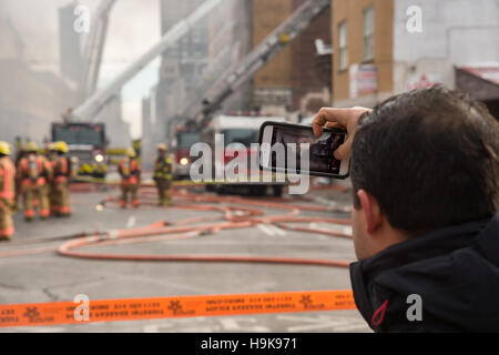 Montreal, Ca - 23. Nov. 2016: männlich Fußgängerzone Bilder nimmt mit Smartphone als Feuerwehrmänner auf 'Cafe Amusement 68' arbeiten Stockfoto