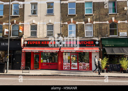 Passanten in Stoke Newington Road vor einem Kebab Restaurant und Metzgerei. In Dalston, East London gedreht. Stockfoto