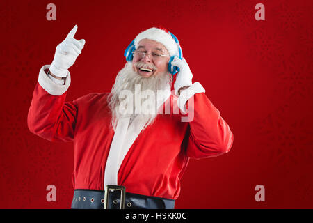 Zusammengesetztes Bild des Weihnachtsmannes Musik über Kopfhörer hören Stockfoto