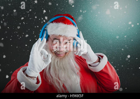 Zusammengesetztes Bild Porträt des Weihnachtsmannes Hand Ordnung Anzeichen beim Musikhören auf headph Stockfoto