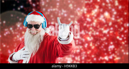 Zusammengesetztes Bild des Weihnachtsmannes Horn Anzeichen beim Musikhören über Kopfhörer Stockfoto