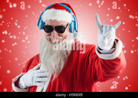 Zusammengesetztes Bild des Weihnachtsmannes Horn Anzeichen beim Musikhören über Kopfhörer Stockfoto