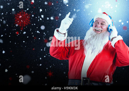 Zusammengesetztes Bild des Weihnachtsmannes Musik über Kopfhörer hören Stockfoto