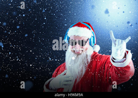 Zusammengesetztes Bild des Weihnachtsmannes Horn Anzeichen beim Musikhören über Kopfhörer Stockfoto
