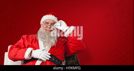 Zusammengesetztes Bild von lächelnden Weihnachtsmann auf Stuhl sitzend Stockfoto