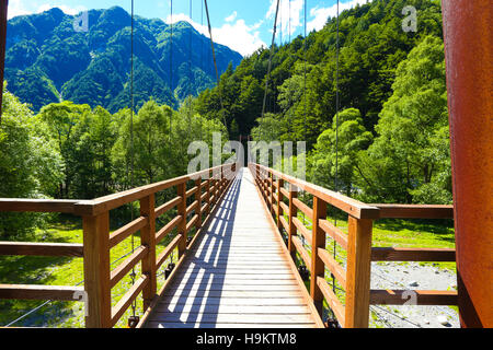 Hölzerne Span Shinmura Bashi Brücke und Berg Hintergrund zentriert auf sonnigen Sommertag im japanischen Alpen Nationalpark, Kamiko Stockfoto