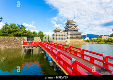 Schöne rote Holzbrücke führt über den Graben Wasser zum Bergfried der Burg Matsumoto Jo an einem sonnigen Sommertag in Nagano, Japan Stockfoto