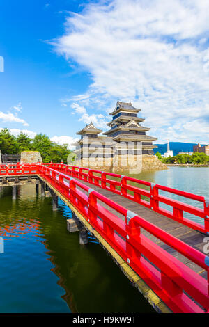 Schöne rote Holzbrücke führt über den Graben Wasser zum Bergfried der Burg Matsumoto an einem sonnigen Sommertag in Nagano, Japan Stockfoto