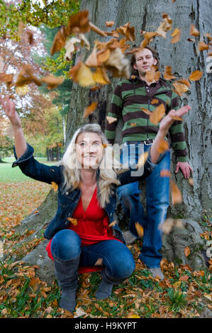Junges Paar werfen herbstliche Blätter Stockfoto