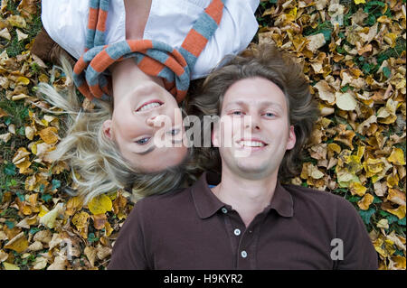 Junges Paar im herbstlichen Blätter liegen Stockfoto