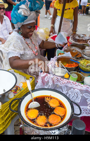 SALVADOR, Brasilien - 2. Februar 2016: Brasilianische Baiana Frau montiert einen Teller mit traditionellen Acaraje Krapfen aus einem Stall. Stockfoto