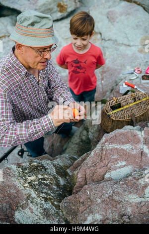 Großvater lehrt Enkel Angeln am Felsenküste Stockfoto