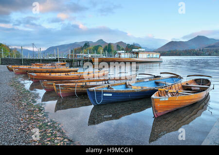 Klassische Ansicht von Holzbooten auf Derwentwater bei Sonnenaufgang gegen Catbells und Causey Hecht, Keswick, Lake District, Großbritannien Stockfoto