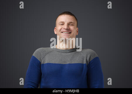 Porträt eines jungen schwulen Männern, lächelt. Emotionale Fotos im Studio auf einem schwarzen Hintergrund Stockfoto