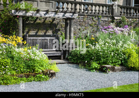 Ein Sitzmöbel Arbor flankiert von krautigen Blumenrabatten in Rydal Hall Cumbria UK Stockfoto