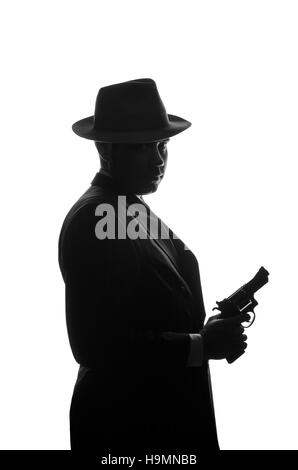 Silhouette der Privatdetektiv mit einer Pistole in der rechten Hand. Agent bleiben Seite auf Kamera und sieht aus wie Mafioso Al Capone. Kriminelle Szene. Studio gedreht Stockfoto