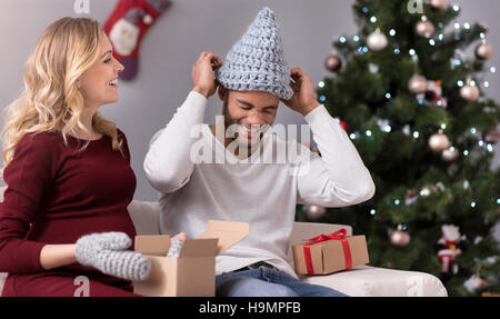 Positiven jungen Mann seinen Kopf eine Mütze aufsetzen Stockfoto