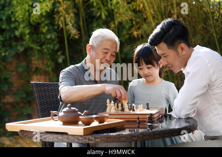 Drei Generationen auf dem Hof spielen Schach Stockfoto