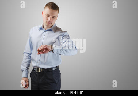 Junger Geschäftsmann befasst sich mit einer Armbanduhr. Isoliert auf weißem Hintergrund. Stockfoto