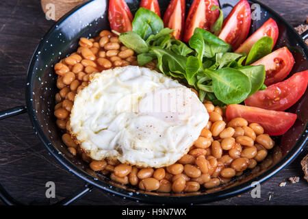 Spiegeleier mit Bohnen, Tomaten und Kräutern. Stockfoto