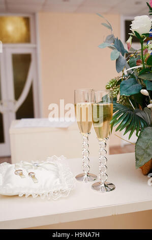 zwei Gläser Champagner und Kissen mit Ringen auf dem Tisch für die Trauung Stockfoto