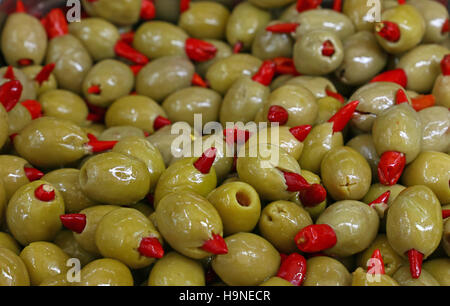 Grüne entkernte Oliven gefüllt mit rote scharfe Chilischoten in Öl Hintergrund, Markt stand Einzelhandel, niedrigen Winkel Ansicht Nahaufnahme Stockfoto