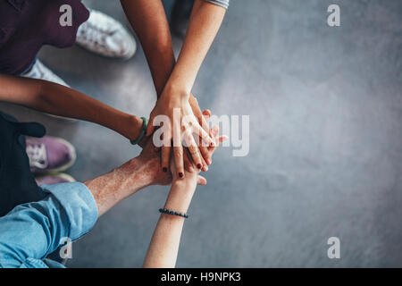 Zugeschnittenes Bild der jungen Menschen die Hände übereinander. Draufsicht der jungen Gruppe mit Händen auf Stapel. Stockfoto