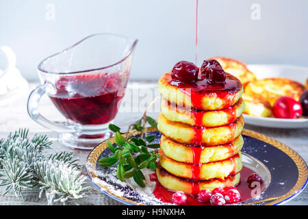 Leckere Quark-Pfannkuchen mit Kirschmarmelade und Preiselbeeren. Traditionelles russisches Frühstück. Selektiven Fokus. Stockfoto