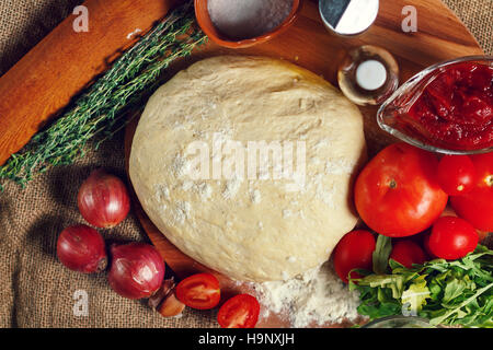 Zutaten für hausgemachte Pizza: Teig, Tomaten, Zwiebeln, Kräutern, Olivenöl. Selektiven Fokus. Stockfoto