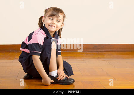 Kleine Schulmädchen ihre Schuhe binden Stockfoto