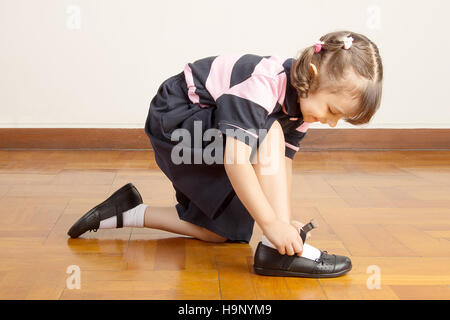 Kleine Schulmädchen ihre Schuhe binden Stockfoto