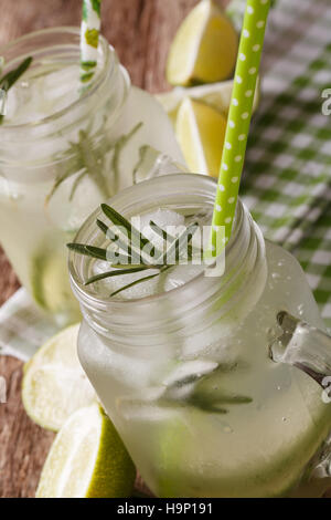 Erfrischungsgetränk mit Kalk, Eis und Rosmarin Makro in einem Glas auf dem Tisch. vertikale Stockfoto