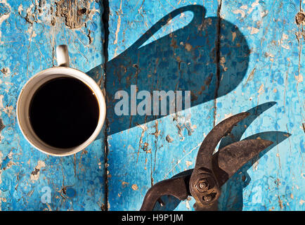 Eine Tasse Kaffee mit der Gartenschere auf den alten blauen Holzbrett in den Frühling Garten, Vintage-Tools auf Tisch, Ansicht von oben. Saisonale Hobby zu Hause. Stockfoto