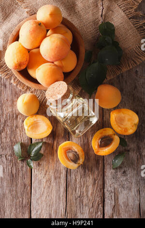Aprikosenkernöl in ein Glas-Glas-Nahaufnahme auf den Tisch und Zutaten. Vertikale Ansicht von oben Stockfoto