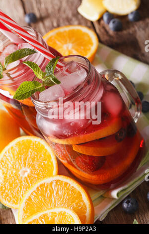 Sommer-Sangria mit Früchten, Eis und Minze hautnah in einem Glas auf dem Tisch. vertikale Stockfoto