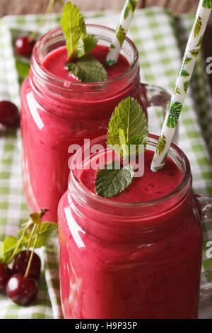 Hausgemachte Kirsch Smoothie mit Minze im Glas-Glas-Makro auf dem Tisch. vertikale Stockfoto