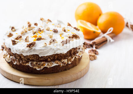 Hausgemachte Karotte und Walnuss-Kuchen mit pikanter orange Sahnehäubchen auf weißer Holztisch Stockfoto