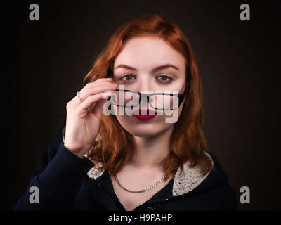 Schöne Nerd Mädchen oder eine junge Frau auf der Suche über Brillen. Vision, Skepsis, Bewertung, Verführung, Bildung und Menschen-Konzept Stockfoto