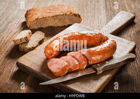 die in Scheiben geschnittenen leckere Wurst mit Brot auf dem Holztisch Stockfoto