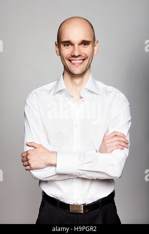 Porträt des jungen lächelnder Mann in die Kamera schaut. Porträt auf grauem Hintergrund. Stockfoto