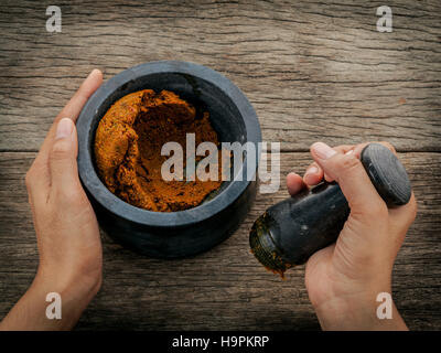 Die Frauen halten Stößel mit Mörtel und und rote Currypaste würzen Stockfoto