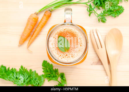 Gläser Karottensaft mit Karotte Wurzeln auf hölzernen Hintergrund. G Stockfoto