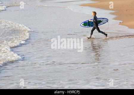 Bournemouth, Dorset, UK. 25. November 2016. UK-Wetter: kalt sonnigen Tag am Strand von Bournemouth. Surfer läuft ins Meer, um die Bedingungen zum Surfen nutzen. Bildnachweis: Carolyn Jenkins/Alamy Live-Nachrichten Stockfoto