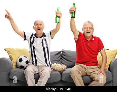 Zwei ältere Männer sitzen auf einem Sofa Fußball gucken aufgeregt und jubeln isoliert auf weißem Hintergrund Stockfoto