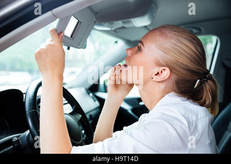 Porträt von eine hübsche junge Geschäftsfrau in Spiegel schauen während der Fahrt Auto hautnah Stockfoto