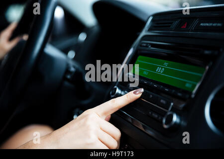 Bild einer Frau Hand Drehen des Radios im Auto beschnitten Stockfoto