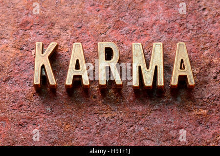 Karma-Wort, das aus metallischen Lettern auf rotem rostige Oberfläche Stockfoto