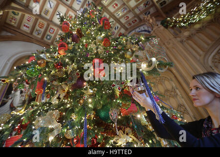 Royal Collection Trust Bedienstete verleiht den letzten Schliff ein 20ft Nordmann-Tanne in St Georges Hall, als Teil der Weihnachtsschmuck in Windsor Castle, Berkshire aufgestellt wird. Stockfoto